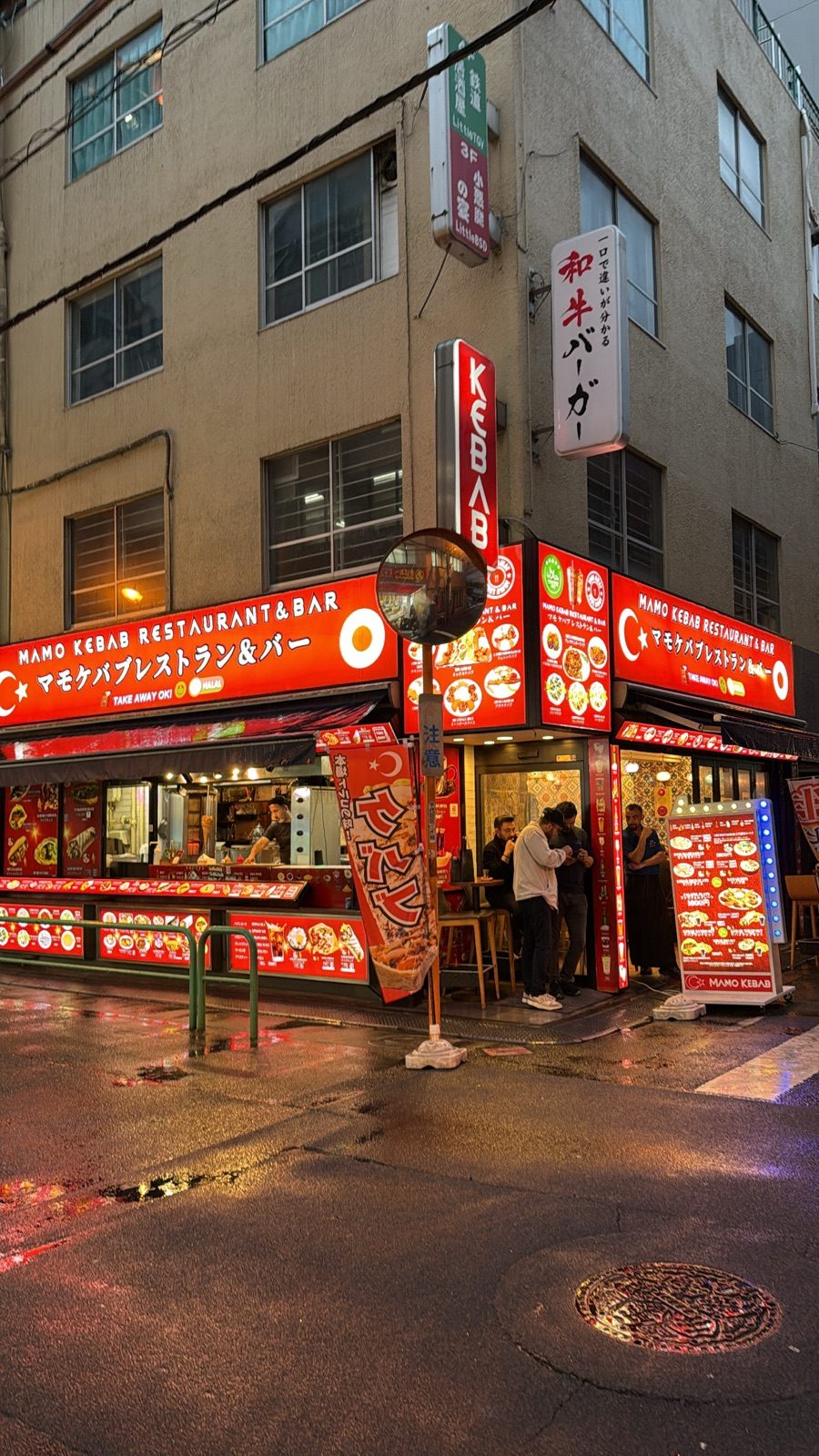 Mamo Kebab restaurant with red signs reflected in the wet pavement