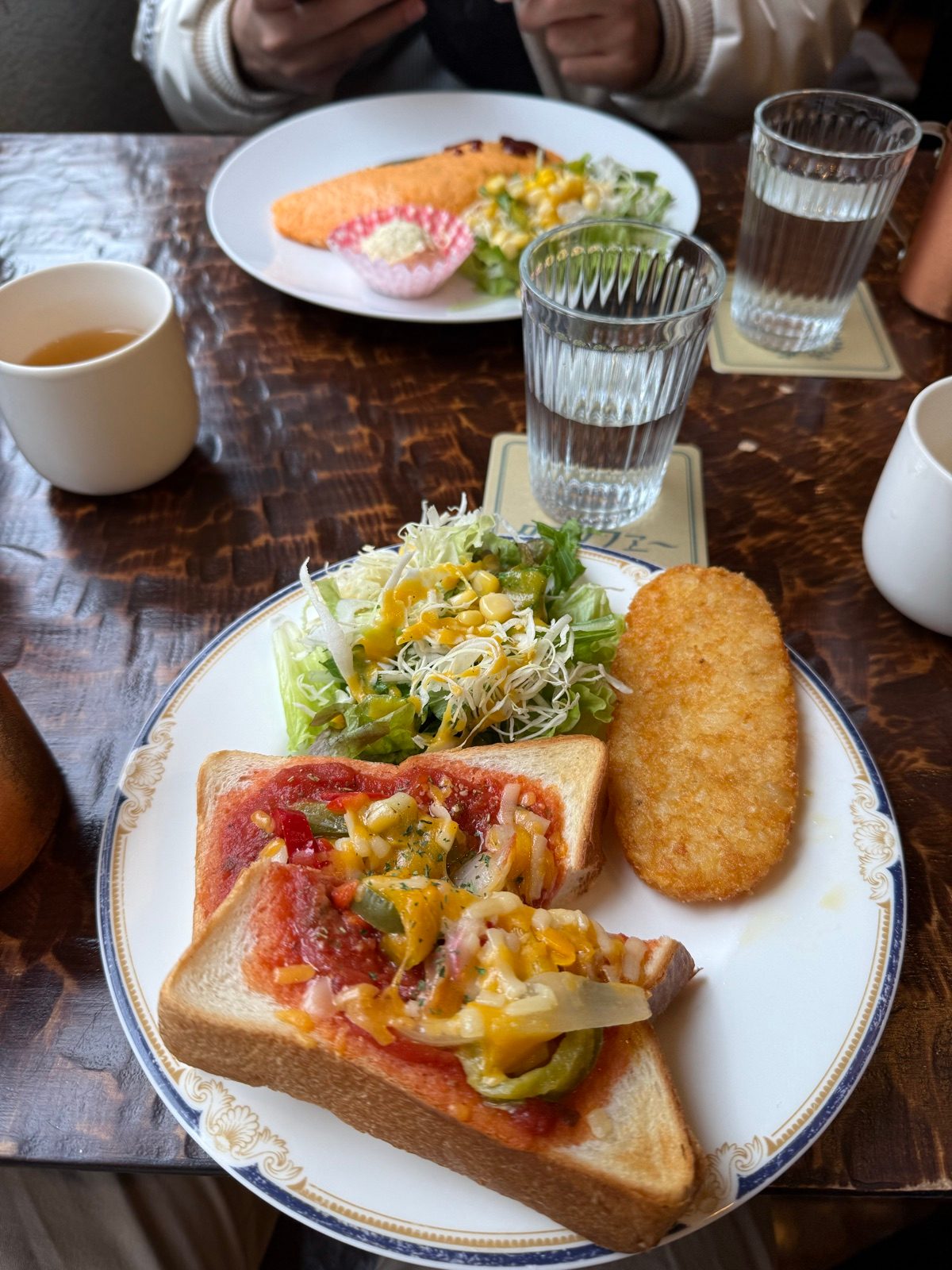 Breakfast with topped toast, shredded cabbage, and a hash brown