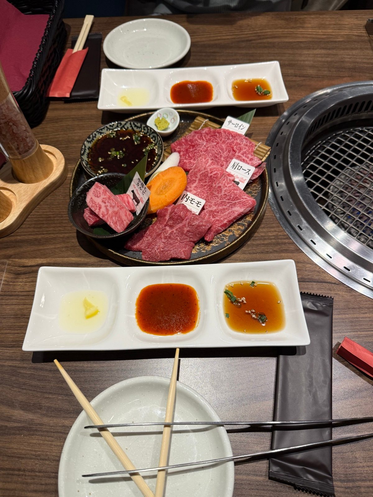 Slices of beef and dipping sauces beside a tabletop grill