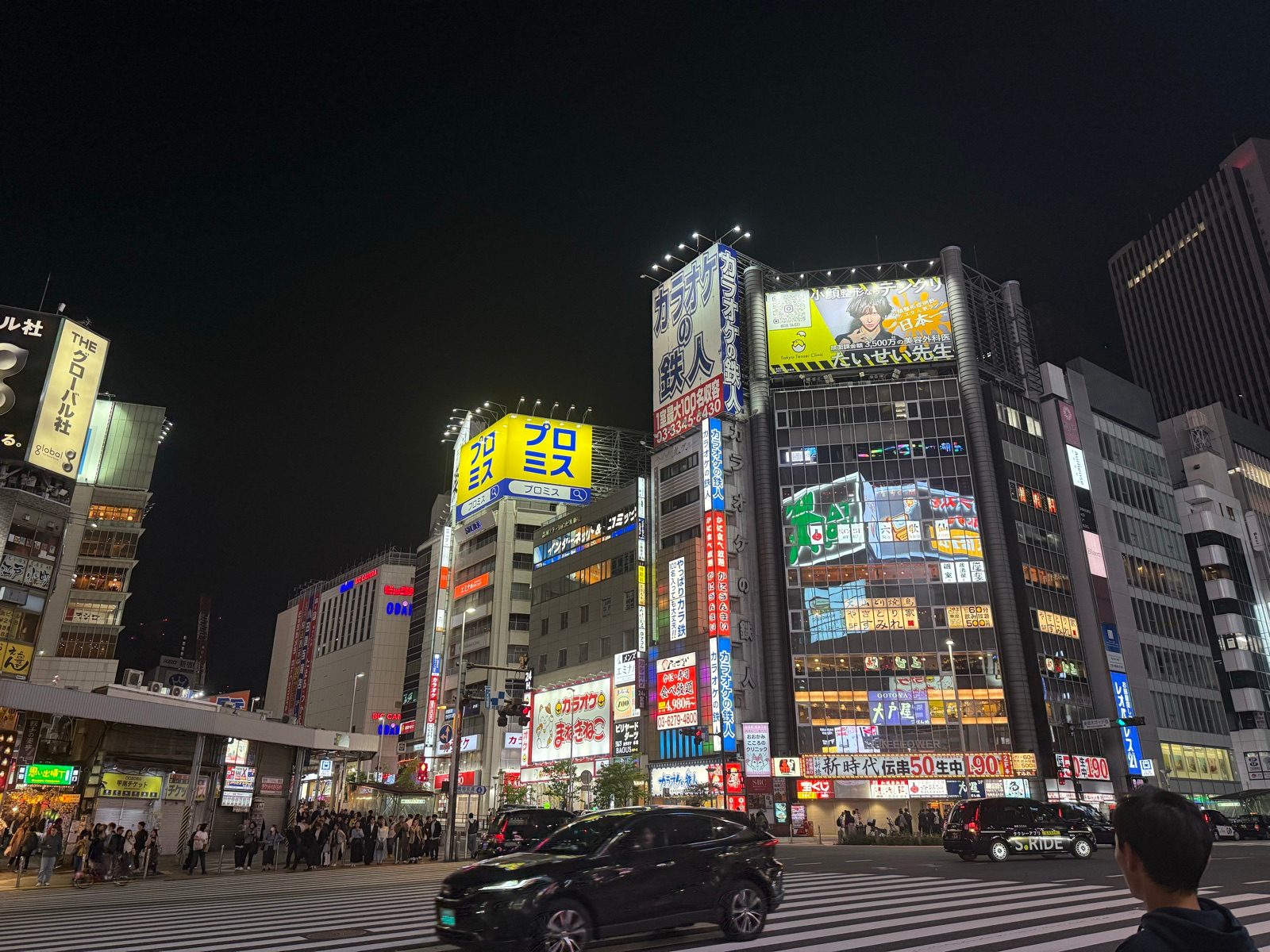 An illuminated city intersection with colorful billboards at night