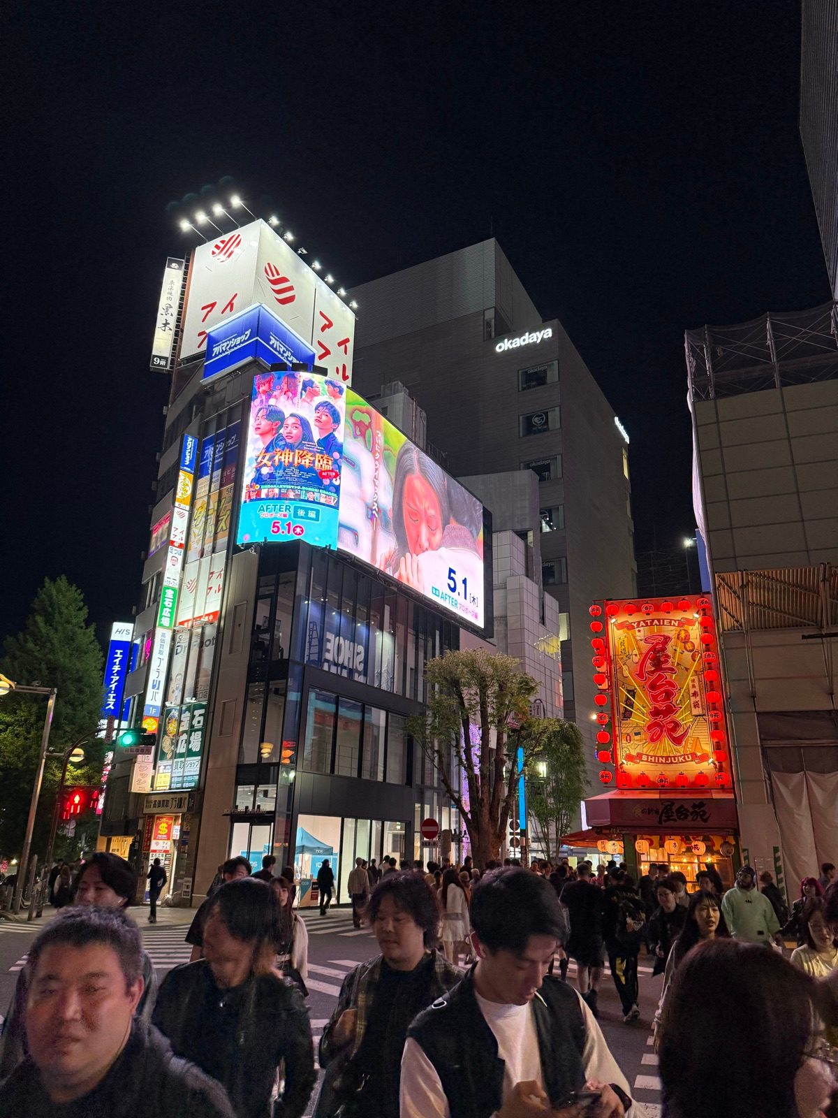 Crowds beneath illuminated billboards on a busy night street
