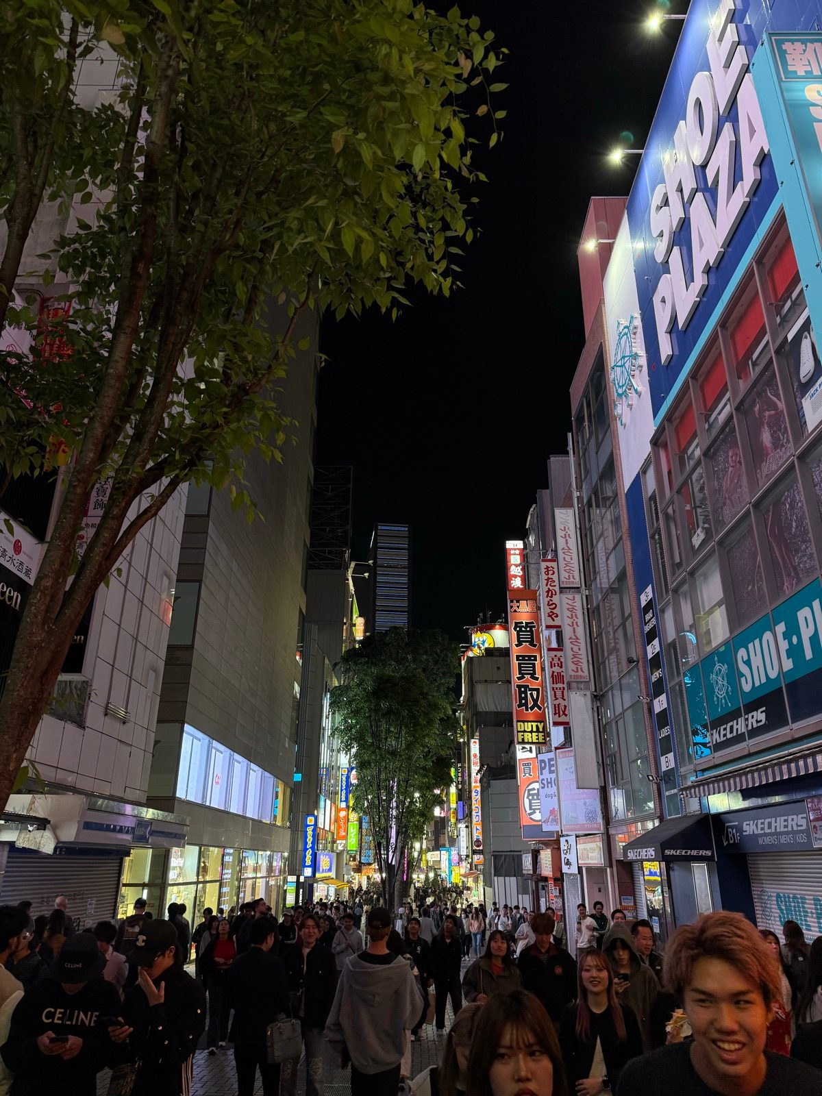 A crowded pedestrian street beneath shop signs at night