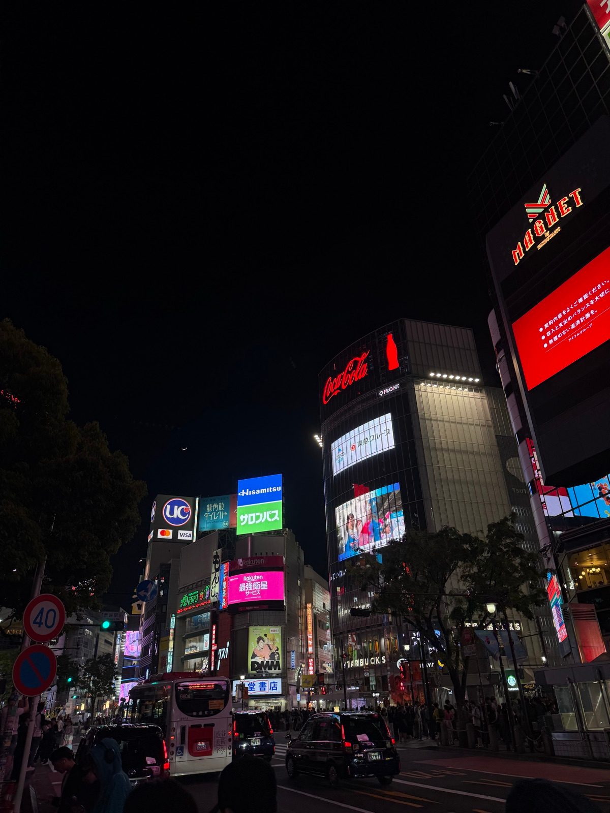 Large illuminated screens above a city street at night