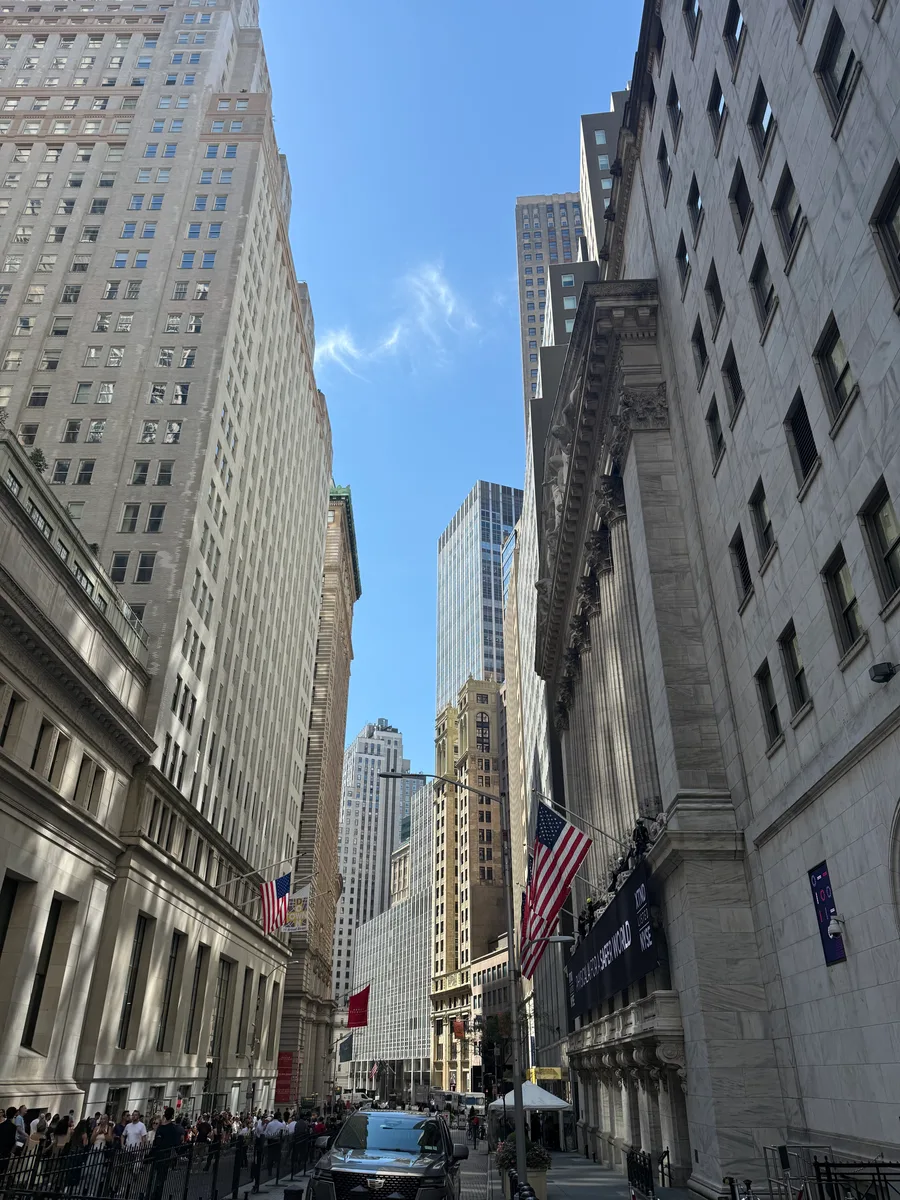 A narrow street between tall stone buildings and American flags