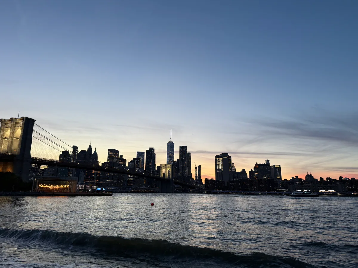 Waves beneath the Brooklyn Bridge with Manhattan silhouetted at dusk