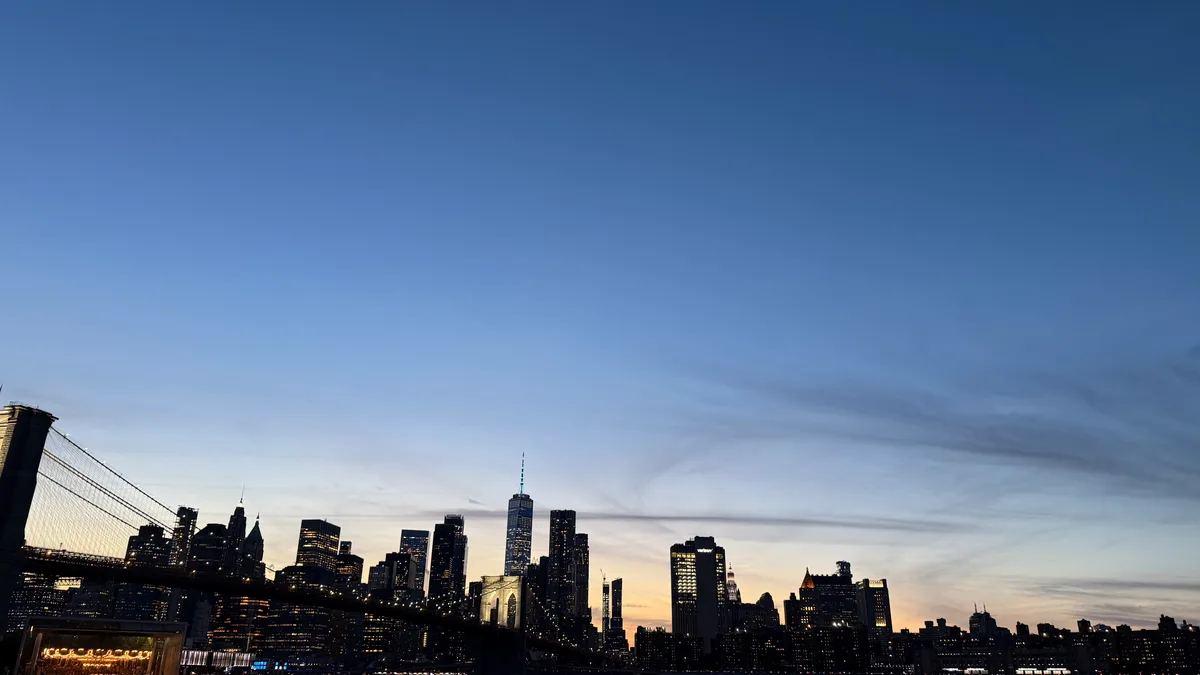 A wide view of the Manhattan skyline and Brooklyn Bridge at dusk