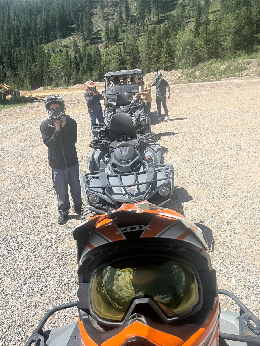 A row of ATVs and riders preparing beside a mountain road
