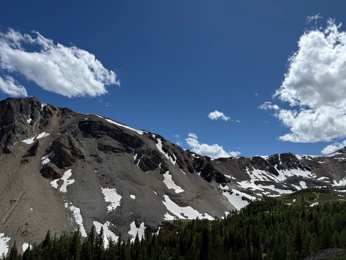 Snow patches on a rugged mountain ridge beneath a blue sky